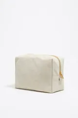 Neceser grande Bimba y Lola color beige, de nylon con estructura blanda y cierre de cremallera. Tiene un bolsillo interior, tirador de piel y logo metálico.