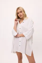 Vestido camisero a rayas verticales de colores pastel, con cuello camisero, cierre frontal con botones y mangas largas.