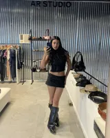 Top negro con escote halter que se ata en la nuca y la espalda, con detalle de nudo en la parte baja de la espalda. La prenda tiene un tejido con textura de terciopelo o jacquard con diseño de arabescos.