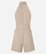 Mono corto color beige, con cuello halter tipo camisa, abotonado en el frente y cinturón con hebilla metálica.
