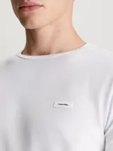 Remera blanca de manga larga Calvin Klein, corte slim, cuello redondo y parche con logo en el pecho.