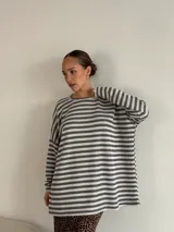 Sweater de punto a rayas horizontales blancas y negras, de corte holgado y mangas largas.