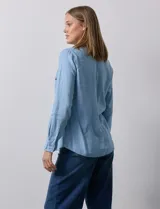 Camisa celeste de lyocell, marca Zac & Rachel. Cuello con solapa y abertura central con botones. Delantera con bolsillos.