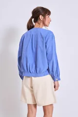 Cazadora color verde oliva con cuello redondo, cierre frontal con botones y mangas largas con puños elásticos.