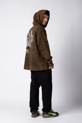 Buzo canguro negro con capucha, de corte oversize y estética lavada. Presenta un bolsillo tipo canguro y puños con orificio para el pulgar. Estampado con texto en el lateral izquierdo.