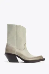 Botín cowboy de cuero color gris claro con efecto desgastado. Tiene caña media, tacón medio ancho y acabado en punta.
