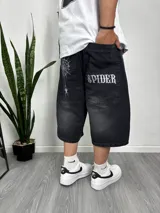 Bermuda de jean negro con corte ancho, bolsillos traseros con la palabra 'SPIDER' estampada en blanco y tela de araña bordada en el muslo izquierdo.