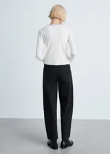 Cárdigan negro de punto de canalé con cuello pico, cierre frontal con botones y ribete blanco en cuello, botones y borde de la abertura.