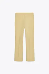 Pantalón color arena de tiro alto con bolsillos delanteros y corte acampanado. Cierre frontal con cremallera y gancho metálico.