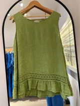 Musculosa sin mangas color verde pistacho, con escote redondo y detalle de encaje calado en el ruedo, que presenta un volante superpuesto.