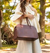 Bolso tipo tote de cuero negro con textura tipo piel de cocodrilo, doble asa de mano y cierre superior con cremallera.