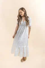 Vestido midi blanco con bordado floral, escote en V con botones, mangas cortas abullonadas con lazos y falda con volantes.