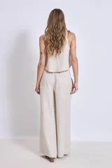 Conjunto de lino color beige, compuesto por un top sin mangas con cuello halter y un pantalón palazzo de tiro alto con cintura elastizada.