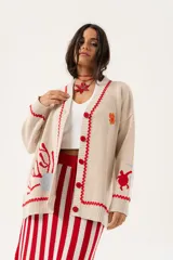 Saco oversize tejido con ilustraciones inspiradas en corales, peces, estrellas de mar y tortugas. Presenta galón picot en rojo en cartera y puños, y botones a tono.