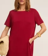 Vestido corto marrón, estilo camiseta, con escote redondo, mangas cortas y bolsillos laterales. El bajo es redondeado.