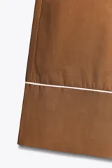 Pantalón marrón de popelina con corte palazzo, tiro medio, cintura elástica ajustable con cordones, bolsillos laterales y falsos bolsillos de vivo con botones en la espalda. Detalle de vivos blancos a contraste en el ruedo.