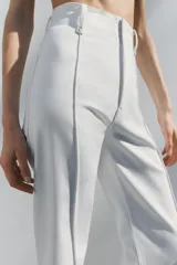 Jeans de tiro alto, pierna ancha y largo al tobillo, en denim celeste claro con efecto lavado. Presenta costura marcada en el centro de cada pierna y cierre frontal con cremallera y botón.