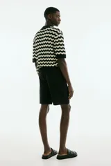 Short negro de tejido suave con cintura elástica y cordón ajustable oculto. Tiene bolsillos laterales discretos y bolsillos traseros ribeteados. Corte relajado.