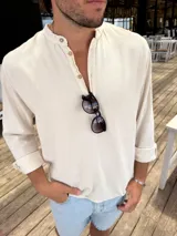 Camisola de lino color beige, con cuello mao y mangas largas con puños abotonados.