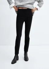 Pantalón negro de corte skinny y largo cropped, confeccionado en tejido fluido con forro interior. Presenta tiro medio, trabillas, bolsillos laterales y traseros de ribete. Cierre frontal con cremallera y botón.
