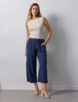 Pantalón crop azul marino de algodón con pretina elastizada, bolsillos inclinados y ruedo lateral con tajo y botones.