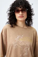 Remerón de manga corta color marrón con efecto lavado y estampa frontal de un caballo con texto estilo western.