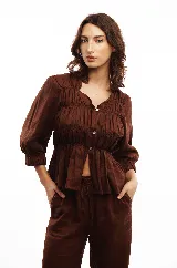 Blusa blanca de lino con escote cuadrado, mangas cortas abullonadas con puños elásticos y cierre frontal con botones de nácar.