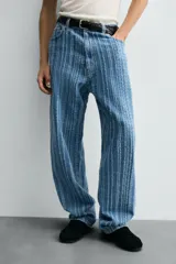 Pantalón de jean azul con rayas verticales texturadas, corte relaxed fit, cinco bolsillos, efecto lavado y cierre frontal con cremallera y botón.
