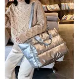 Bolso plateado tipo tote bag, con diseño acolchado horizontal y doble asa de hombro. Incluye correa larga regulable y extraíble.