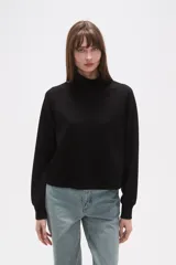 Buzo negro de manga larga con cuello tortuga y corte holgado.