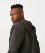 Campera de algodón gris oscuro jaspeado, con cierre frontal de cremallera, capucha con cordones trenzados y bolsillo canguro.