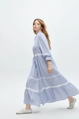 Vestido camisero midi color beige a rayas verticales, con cuello mao, mangas 3/4 abullonadas y festones de algodón en el cuerpo. Cierre frontal con botones.