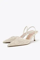 Zapato destalonado color blanco hueso, con tacón fino y punta fina. Capellada de mesh con bordados florales.