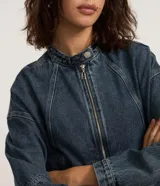 Campera de jean azul con cuello alto, cierre frontal con cremallera, mangas largas y recortes.