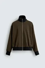 Sudadera color verde militar con cuello perkins, cierre frontal con cremallera, bolsillos de vivo en cadera, manga larga con banda a contraste en color crema y acabados en rib a contraste en color negro.