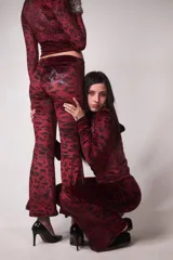 Conjunto de buzo y pantalón de terciopelo rojo con estampado animal print negro. El buzo es de corte cropped con cuello alto y cierre frontal. El pantalón es acampanado y tiene un aplique de estrella en la parte trasera.