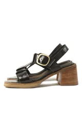 Sandalias de cuero charol negro con tiras entrecruzadas, hebilla dorada y tacón de madera.