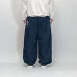 Pantalón de jean azul oscuro, corte ultra baggy, con costuras blancas a contraste y un rayo bordado en el bolsillo lateral.