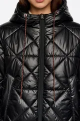 Abrigo largo de corte recto en tejido técnico negro con diseño acolchado de rombos. Presenta capucha integrada con cordones de ajuste, cierre frontal de cremallera, bolsillos laterales de vivo y mangas largas con puños elásticos. El bajo cuenta con elástico y stoppers interiores para un ajuste personalizado.