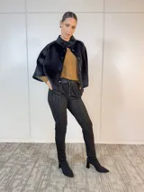 Chaqueta corta negra de terciopelo con cuello alto, manga corta y cierre frontal con botones grandes.