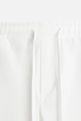 Pantalón de jogging color beige confeccionado en tejido de mezcla de algodón. Cuenta con cintura elástica ajustable con cordón, bolsillos frontales y traseros.