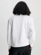 Buzo blanco de felpa de algodón con cuello redondo, puños y bajo acanalados. Estampado vertical con el logo de Calvin Klein Jeans en celeste en el lateral.