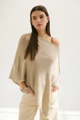 Poncho color beige de tejido de punto con cuello asimétrico.