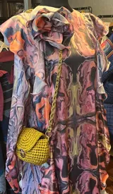 Cartera tejida a mano con trapillo color dorado, con forma estructurada y herrajes dorados. Incluye cadena dorada para colgar del hombro.