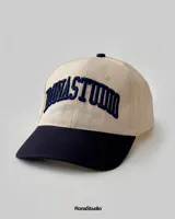 Gorra de béisbol beige con visera y botón superior azul marino. Presenta bordado frontal en azul marino con la inscripción "Bonastun South American League".