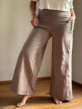 Pantalón palazzo color marrón claro, confeccionado en lycra de algodón, con tiro alto, bolsillos laterales y faja ancha en la cintura.