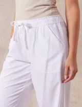 Pantalón largo de lino y rayón a rayas verticales grises y blancas. Tiene pretina elastizada con lazo de ajuste, bolsillos delanteros y traseros.