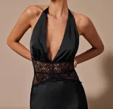 Vestido largo negro de satén con escote halter pronunciado y detalle de encaje en la cintura.