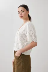 Blusa color crudo de broderie con escote en V y cierre frontal con lazos.