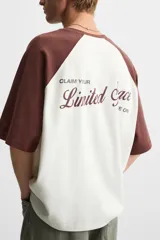 Camiseta blanca con mangas cortas marrones tipo ranglán, cuello redondo y estampado con la frase "Inner Peace" en marrón.